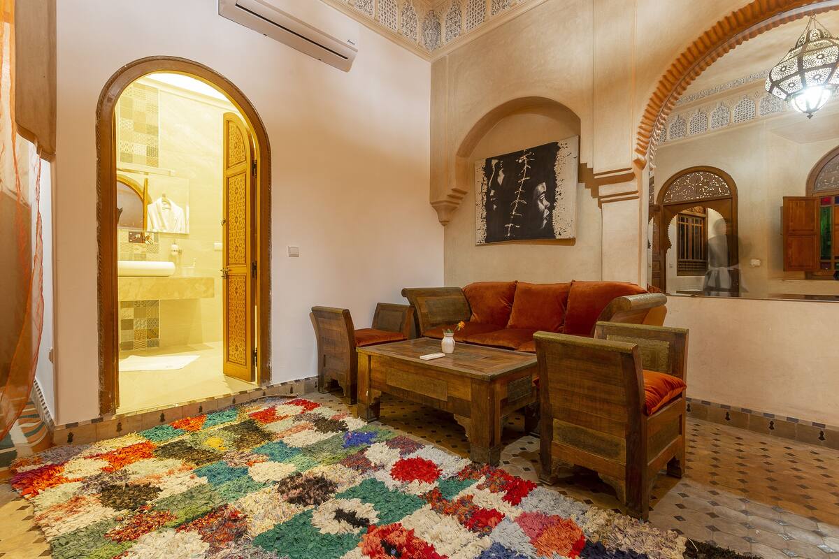 A traditional interior with a wooden sofa, a patterned rug, and a tiled floor.