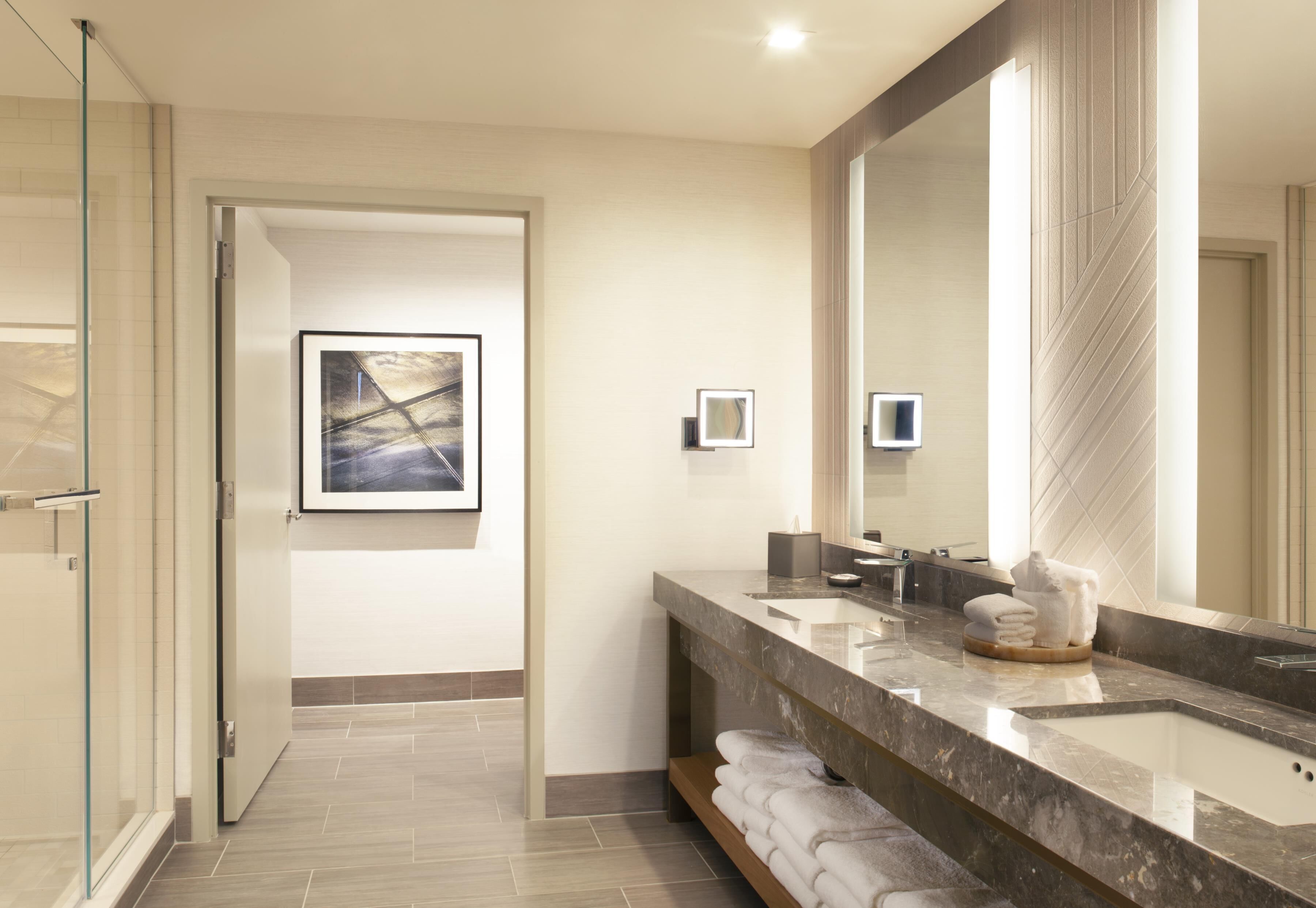 A modern bathroom with a large mirror, a sink, and a shower area.
