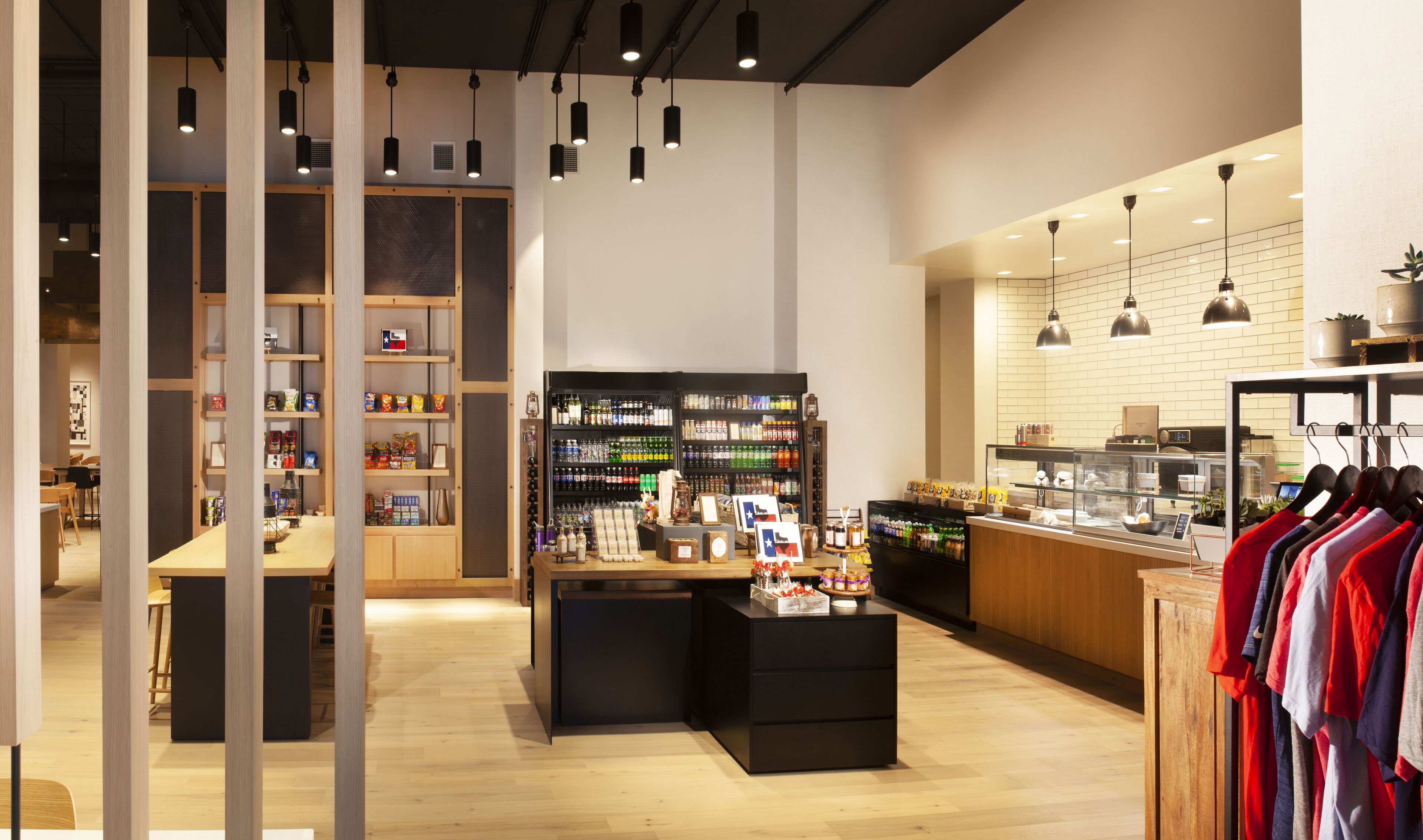 Un espacio comercial moderno con estanterías de madera, una barra con diversos productos y un perchero para ropa.