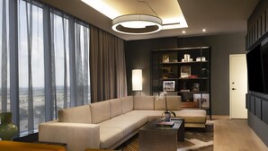 Un salon moderne avec un canapé d’angle, une table basse, une bibliothèque et une grande fenêtre avec des rideaux.