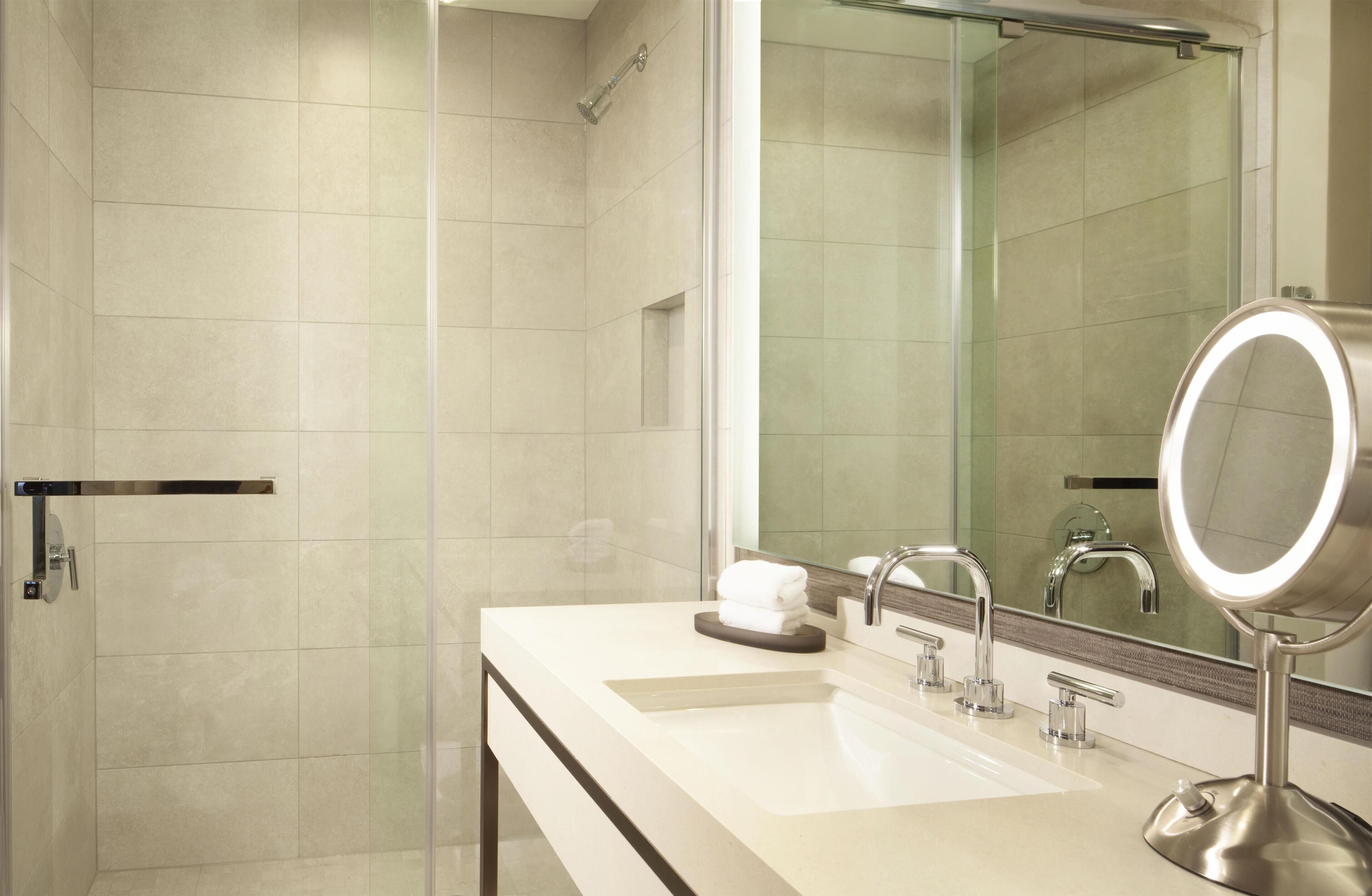 A modern bathroom with a glass shower enclosure, a large mirror, and a dual sink vanity.