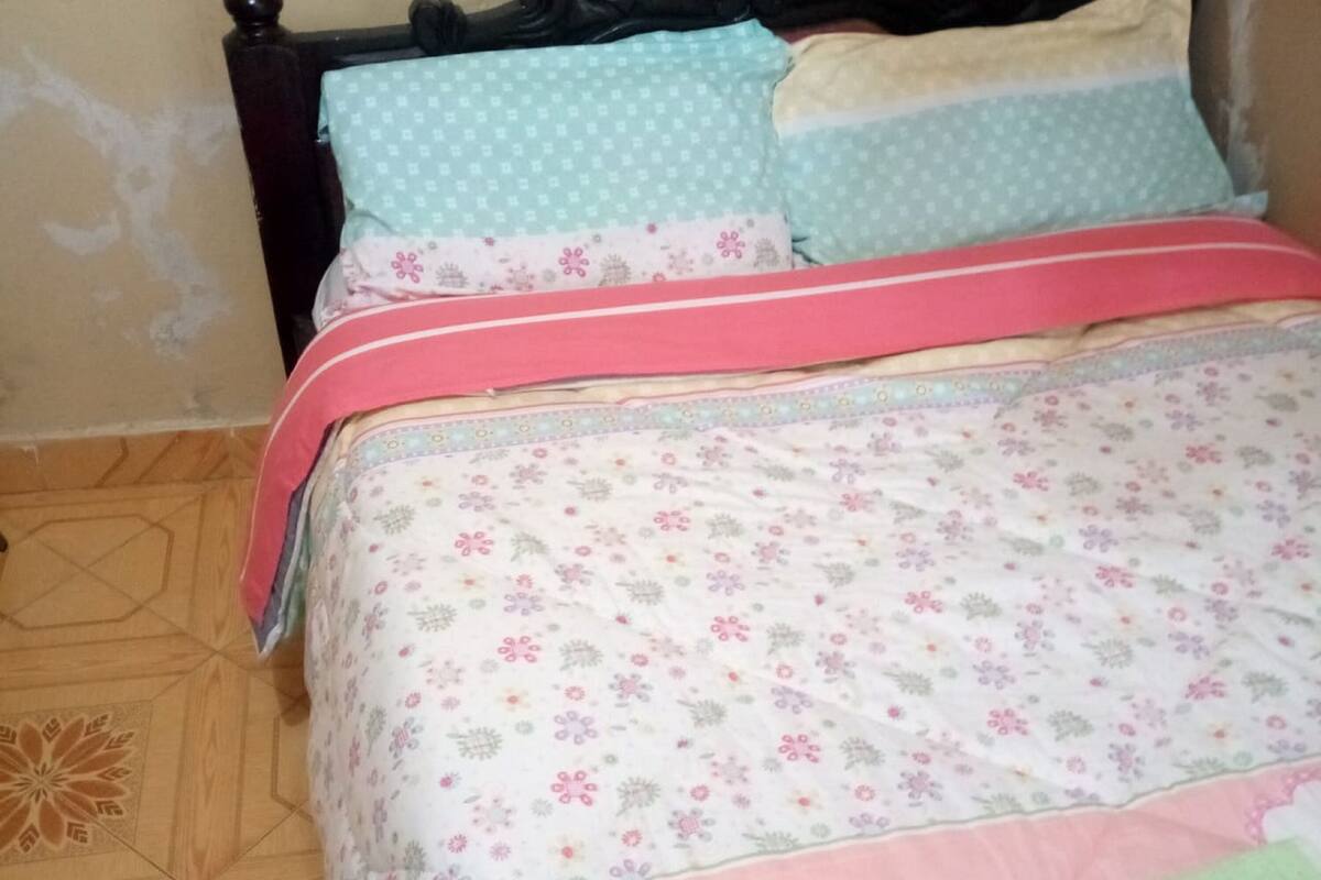 A bed with floral bedding and a pink headboard.