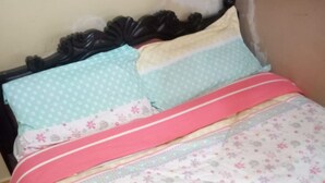 A bed with a floral-patterned bedspread, a pink blanket, and two pillows with different patterns. - Amigos Guest House (Nakuru)