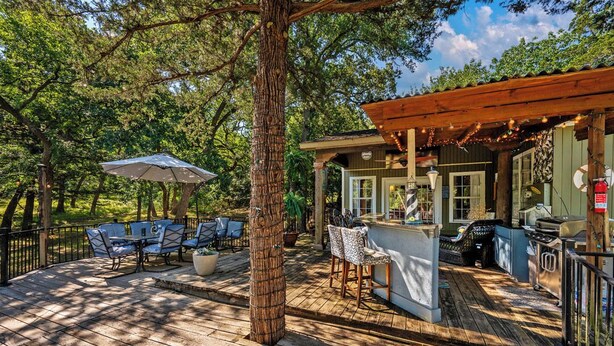 A wooden deck with outdoor seating, a bar area, and a pergola with string lights.
