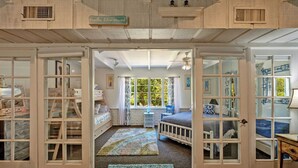 A room with a large window, a bed, a dresser, and a rug.