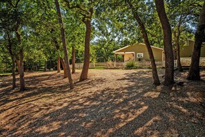 A house surrounded by trees with a gravel driveway and a white picket fence. - Texoma/Tanglewood Highport Marina - Adorable Cottage!
(Pottsboro)