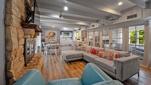 A spacious living area with a stone fireplace, a large sectional sofa, and a dining area in the background.
