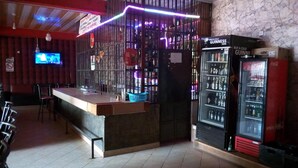 A bar area with a counter, seating, and a television screen. - Bahamas Resort (Thika)