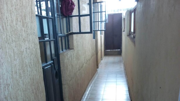 A corridor with tiled flooring and a door at the end. - Bahamas Resort (Thika)