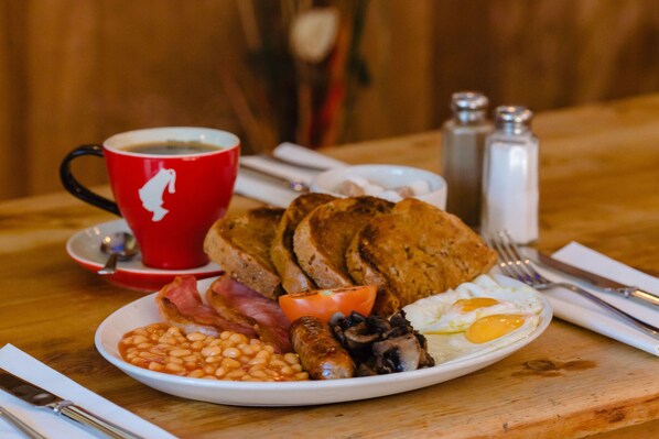Un plato de desayuno con frijoles, salchichas, huevos y tostadas.