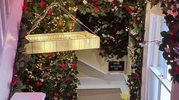 Una escalera con un letrero de neón que dice 'All You Need Is Love' y un cartel que indica que es solo para huéspedes del hotel.