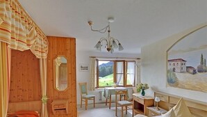 A cozy bedroom with a wooden door, a bed, a desk, and a chair. - Ferienwohnung Watzmannblick 55 qm, 1 sep. Schlafzimmer 2-3 Pers. (Berchtesgaden)