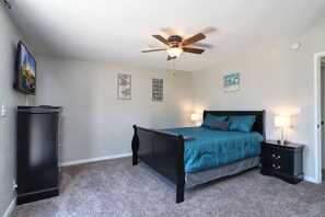 A bedroom with a bed, a ceiling fan, a nightstand, and a dresser. - Spacious Remodel-Great Freeway access-Sleeps 12 (Tucson)