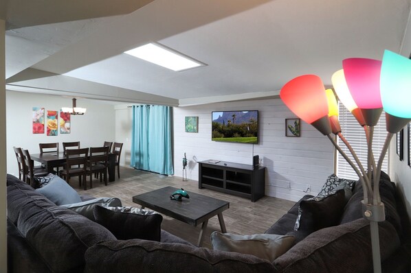A living room with a sofa, coffee table, TV, and artwork on the wall. - Spacious Remodel-Great Freeway access-Sleeps 12 (Tucson)
