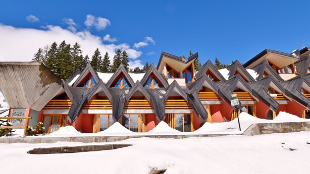 Una hilera de edificios de estilo chalé con tejados inclinados y balcones de madera, rodeados de nieve.