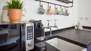 Una cocina moderna con una cafetera, una planta en maceta y un escurreplatos.