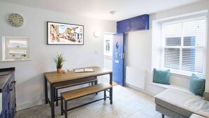 Una habitación con una mesa de madera, un banco, un armario azul y una ventana con persianas.