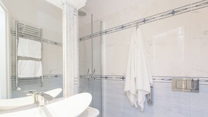 Une salle de bain moderne avec une douche à parois de verre, un lavabo blanc et un miroir.