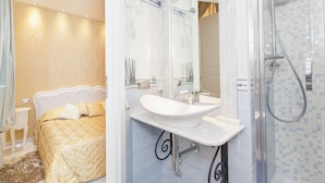 Une chambre d’hôtel avec un lit, une salle de bain avec un lavabo et une douche.