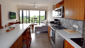 A modern kitchen with a gas stove, microwave, and a dining area with a view. - Agaves 203 (Santa María Huatulco)