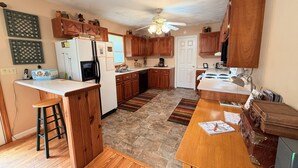 Une cuisine dotée de meubles en bois, d’un réfrigérateur, d’une cuisinière et d’un coin repas avec une table et des chaises.