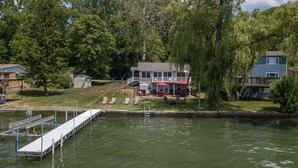 Une propriété au bord du lac, dotée d’un quai, d’une maison avec une véranda et d’un petit abri de jardin.