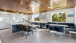 A modern kitchen with a central island, built-in appliances, and a dining area with a bench and chairs. - Steps to Beach-Full gulf views infinity pool-EXQUISITE! Ask @ seasonal specials! (Longboat Key)