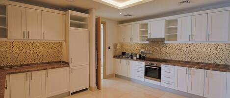 Una cocina moderna con gabinetes blancos, salpicadero de azulejos y horno empotrado.
