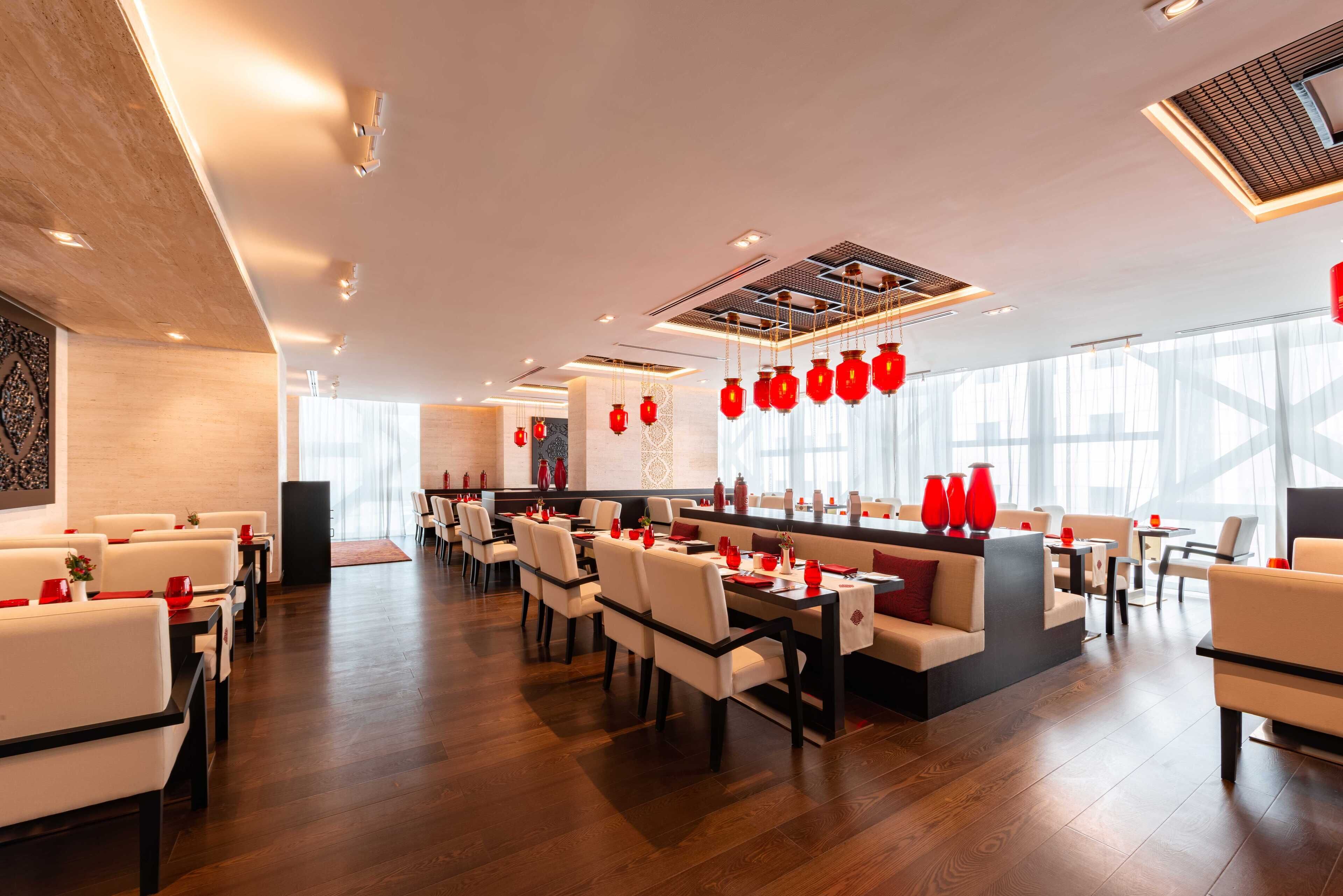 Un restaurante moderno con barra central, asientos blancos y detalles en rojo.