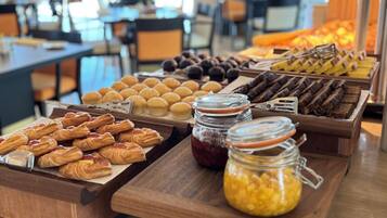 A buffet with various pastries and desserts, including croissants, muffins, and brownies, arranged on wooden serving boards.