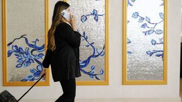 A person in a black pinstripe suit with a briefcase, standing in front of a wall with large, framed floral artwork.