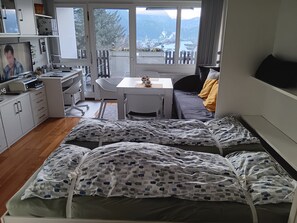 Ein Zimmer mit einem Bett, einem Schreibtisch und einem Stuhl. Ein Fenster bietet Blick auf Berge.