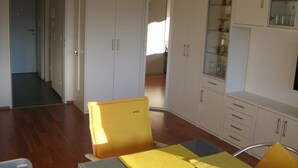 Ein geräumiges Zimmer mit Holzboden, einem Esstisch mit gelben Platzsets und weißen Schränken mit Glastüren.