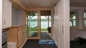 Een kamer met uitzicht op een meer, een schuifdeur naar een terras en een bed met een bedekt patroon.