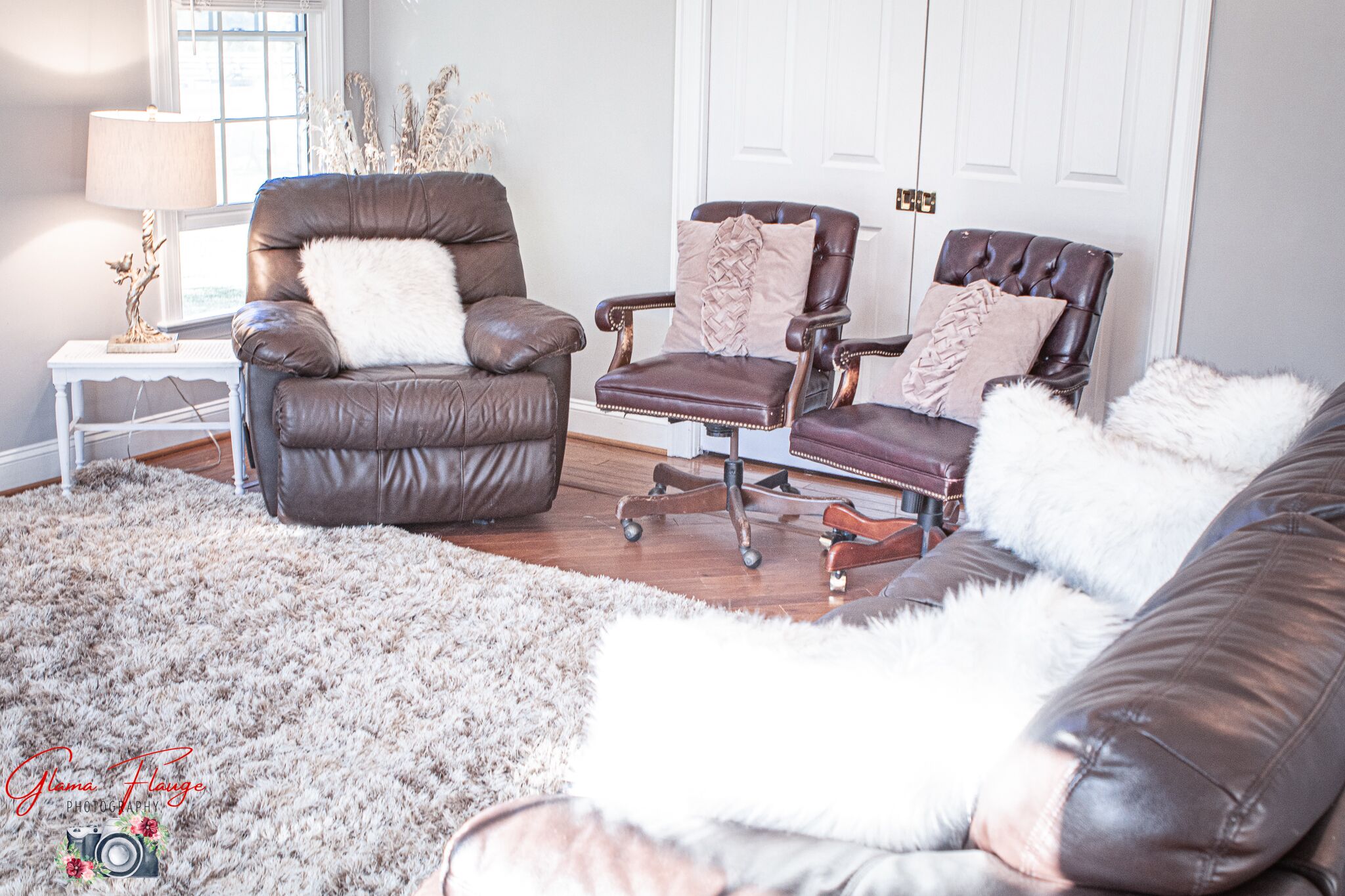 Een woonkamer met een bruine leren bank, een bruine leren fauteuil en een bruine leren slaapbank. Op de vloer ligt een zacht, wit tapijt.