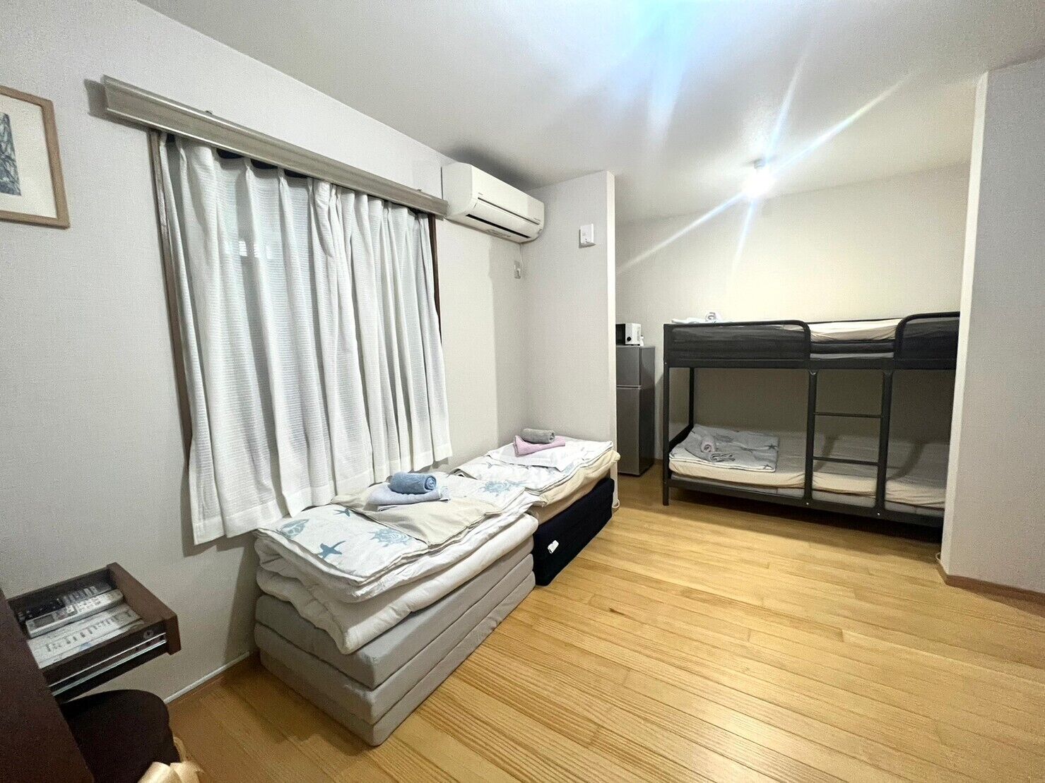 A compact room with a bed, a small desk, a heater, and a bunk bed.