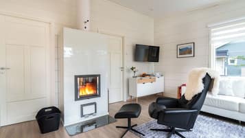 Un salon moderne doté d’une cheminée, d’un téléviseur à écran plat et d’un coin salon confortable.