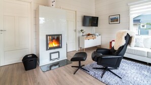A modern living room with a fireplace, a sofa, a TV, and a dining area. - Villa taiga by Interhome (Raattama)