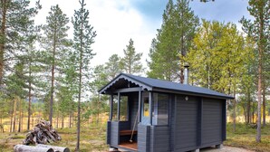 A cabin with a porch, a chimney, and a log pile. - Villa taiga by Interhome (Raattama)