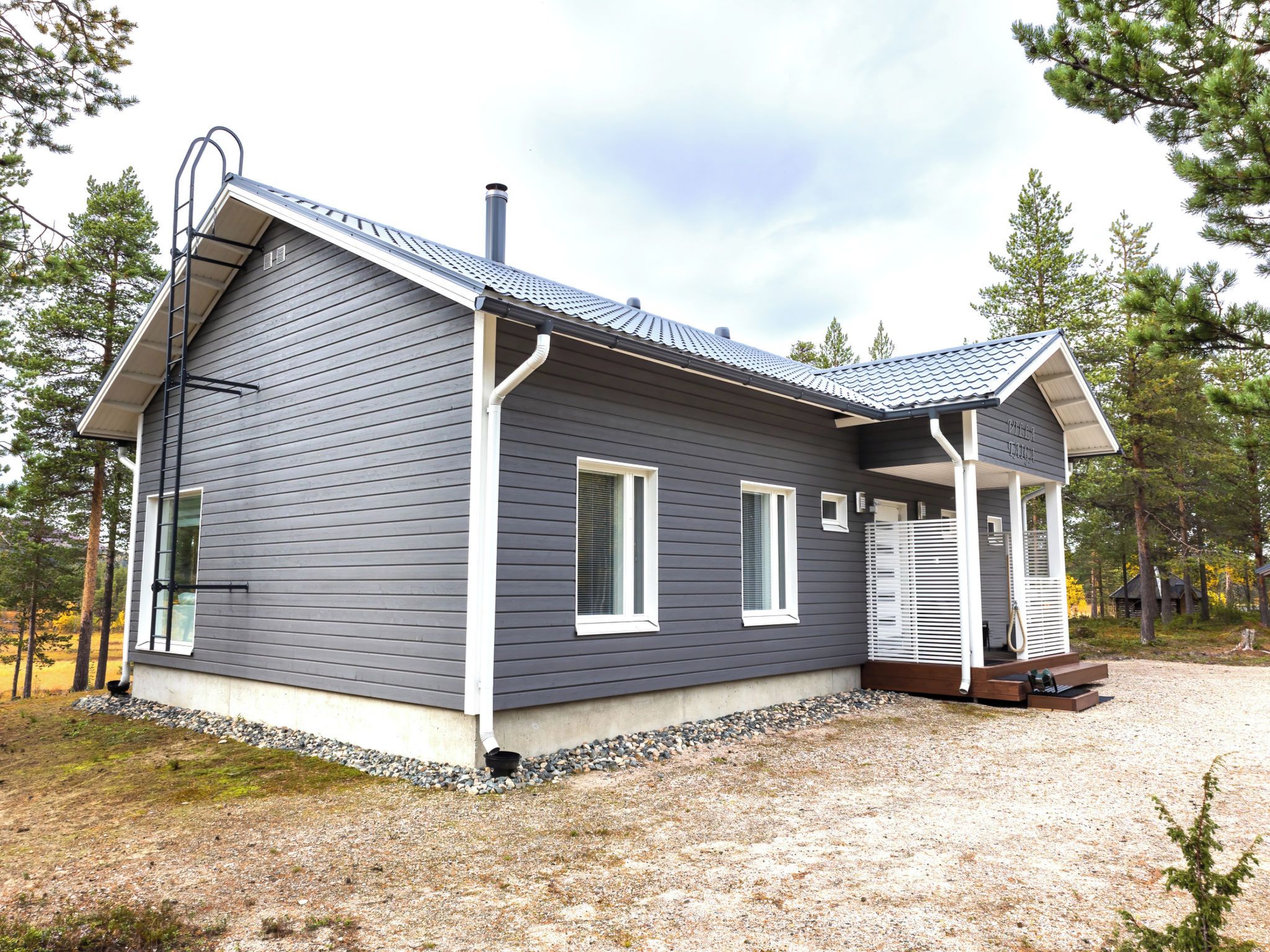 Une maison moderne à deux étages, avec un revêtement extérieur foncé, des éléments décoratifs blancs et un porche abrité.