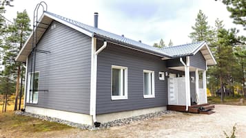 Une maison moderne à deux étages, avec un revêtement extérieur foncé, des éléments décoratifs blancs et un porche abrité.