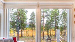 A room with a large window offering a view of a forested area. - Villa taiga by Interhome (Raattama)