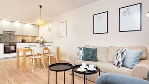 Una sala moderna con un sofá, dos mesas auxiliares y un comedor con sillas y una mesa.