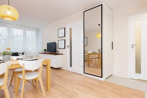 A modern kitchen with wooden cabinets, a dining table with chairs, and a large mirror on the wall.