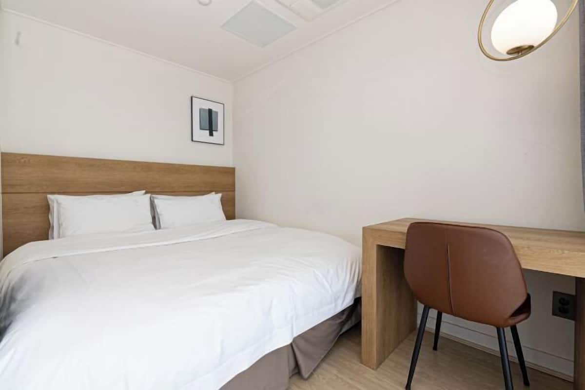 Ein Schlafzimmer mit Bett, Schreibtisch und Stuhl.