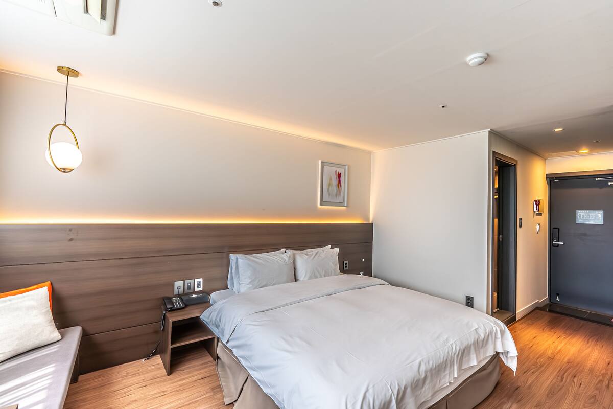 Ein modernes Hotelzimmer mit einem großen Bett, einem Nachttisch und einer Wandleuchte.
