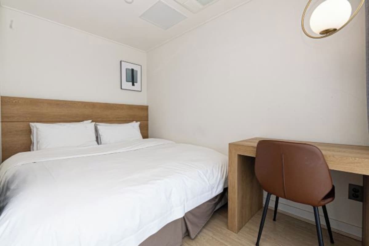 Um quarto com uma cama, uma escrivaninha e uma cadeira.