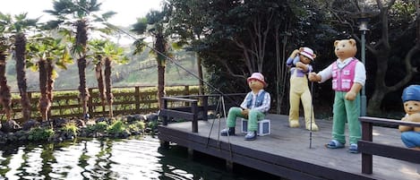 Una terraza de madera con un estanque, palmeras y estatuas de osos.