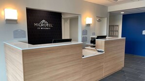A reception desk with a sign reading "MICROTEL BY WYNDHAM" and a check-in/out time sign. - Microtel Inn & Suites by Wyndham Fountain/Fort Carson (Fountain)
