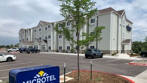 A Microtel by Wyndham hotel with a parking lot and a sign indicating the entrance. - Microtel Inn & Suites by Wyndham Fountain/Fort Carson (Fountain)